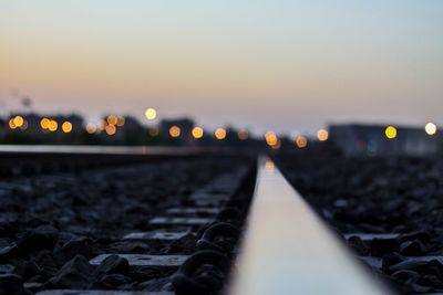 Close-up of illuminated railroad tracks against sky at night