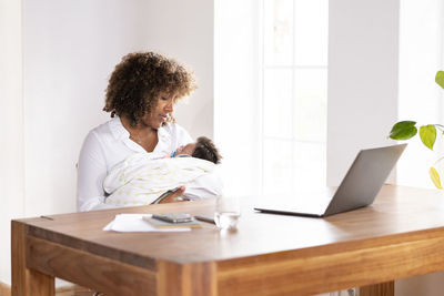 Woman using phone while sitting on table