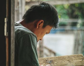 Side view of young man looking through window