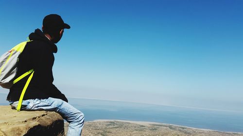 Man looking at sea against blue sky
