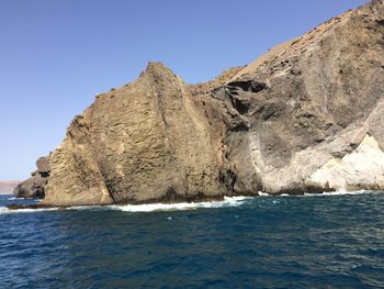 Scenic view of sea and rocks against clear blue sky