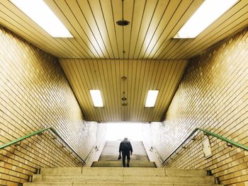 Rear view of man walking on illuminated steps at subway station