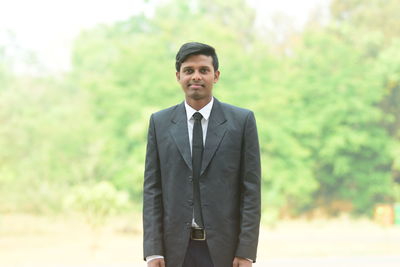 Portrait of young man wearing suit standing outdoors