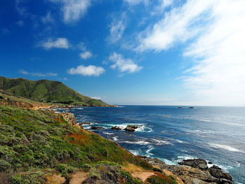 Scenic view of mountains by sea against blue sky