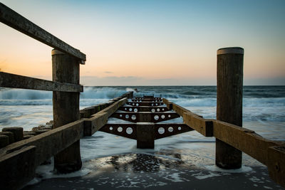 Pier over sea against sky during sunset