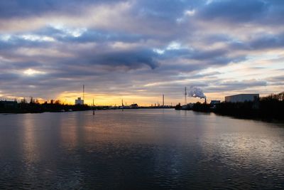 Scenic view of river against cloudy sky at sunset