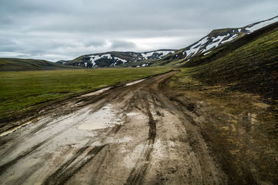 Road leading towards mountains against sky