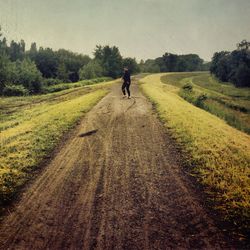 Rear view of person walking on dirt road