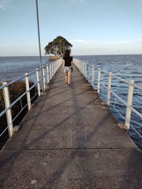 Rear view of woman on sea against sky