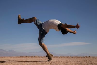 Low angle view of woman jumping against clear sky