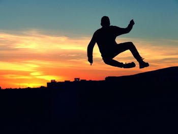 Silhouette of man jumping against sky during sunset