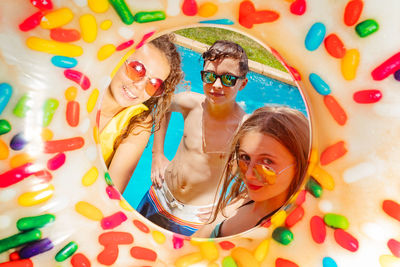 Portrait of smiling teenagers looking through inflatable pool ring