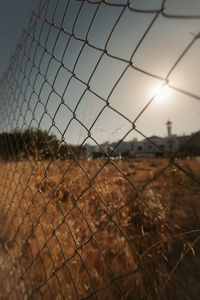 Close-up of chainlink fence against sky during sunset