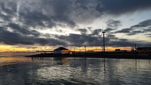 Silhouette built structure by sea against sky during sunset