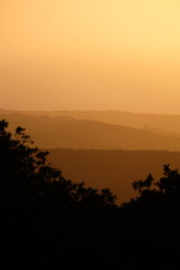 Scenic view of silhouette landscape against orange sky