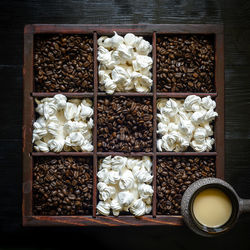 Roasted coffee beans and meringue kisses  laid out in a box in checkered pattern, coffee cup 