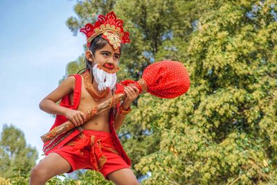 Portrait of woman holding red umbrella against trees