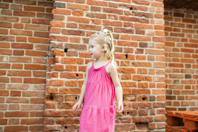 Young woman standing against brick wall