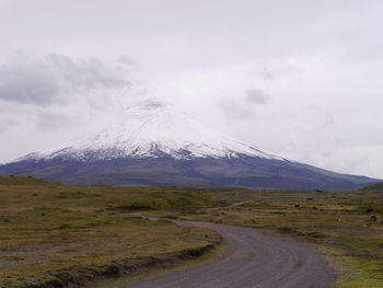 Road by snowcapped mountain against sky