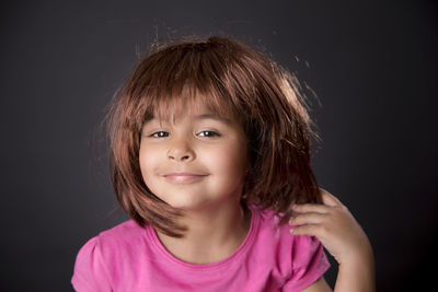 Portrait of smiling girl against black background