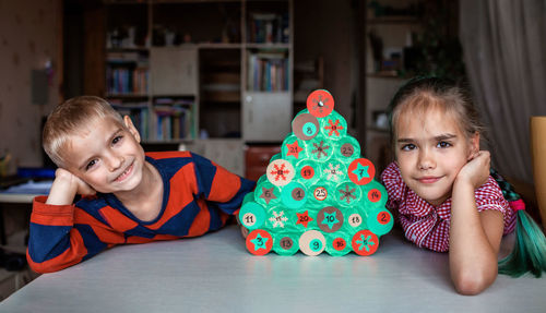 Portrait of cute kids looking at christmas tree at home