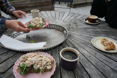 High angle view of people eating prawn sandwich and cinnamon roll with coffee at cafe