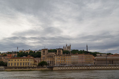 Buildings in city against cloudy sky