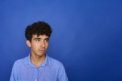 Portrait of young man standing against blue background