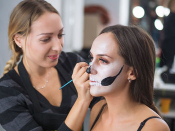 Beautician applying make-up to young woman