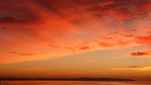 Scenic view of sea against dramatic sky during sunset