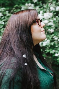 Close-up of young woman looking away while standing by plants