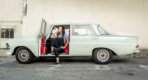 Full length of woman sitting in vintage car
