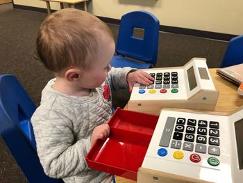 Baby girl playing with toy cash register on table