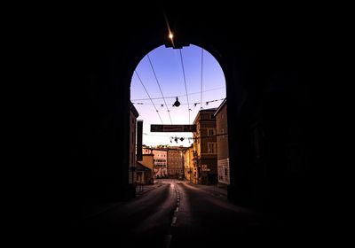 Illuminated city against sky seen through archway