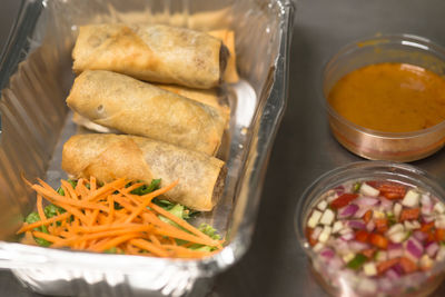 High angle view of spring rolls in foil container on table