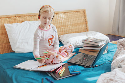  girl child sitting in bed and learning online on a laptopvirtual class lesson on video at quarantine