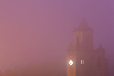 Illuminated building against sky during sunset