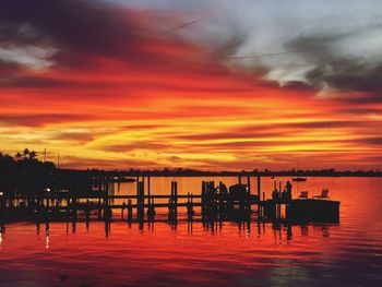 Silhouette pier on lake against orange sky