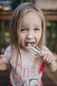 Portrait of girl licking cream from whisk