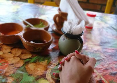 Cropped image of woman with hands clasped by bowls at table