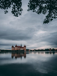 Reflection of building in lake against cloudy sky