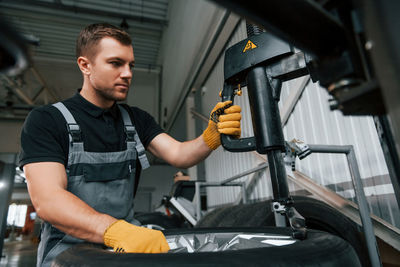 Strong hands. man in uniform is working in the auto service.