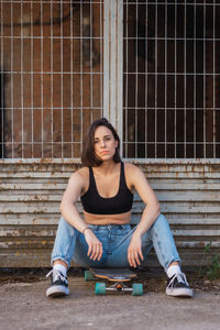 Young woman sitting on skateboard