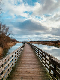 View of footbridge leading to water against sky