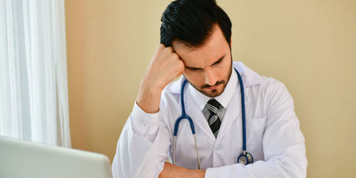 Close-up of thoughtful male doctor sitting in clinic