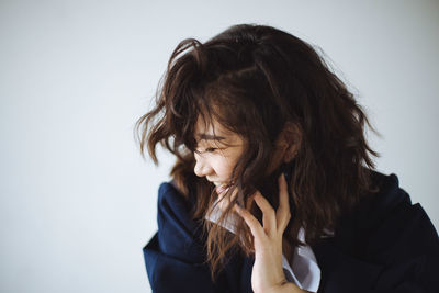 Close-up of young woman sitting against white background