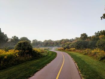 Road amidst trees against clear sky