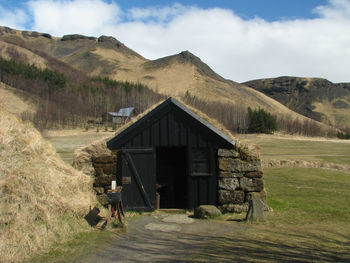 Icelandic cottage in a grassy field with mountains in the background