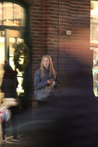 Woman sitting by window in city