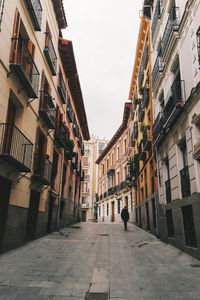 Rear view of woman walking on street amidst buildings in city